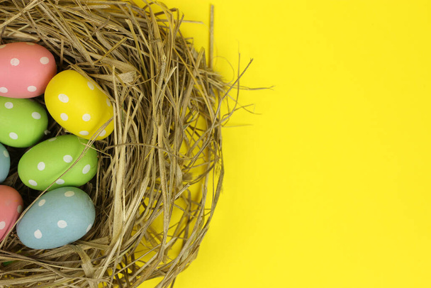 Цветные пасхальные яйца в гнезде на желтом фоне
 - Фото, изображение