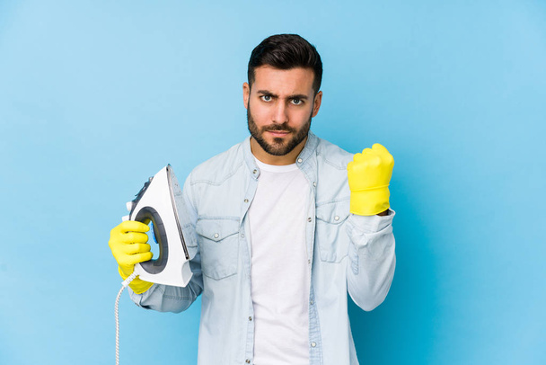 Portrait of young man ironing isolated showing fist to camera, aggressive facial expression. - Fotografie, Obrázek