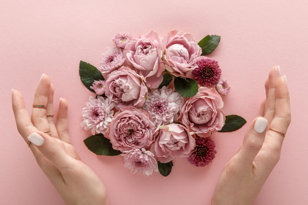top view of blooming spring flowers and female hands on pink background - Foto, Imagen