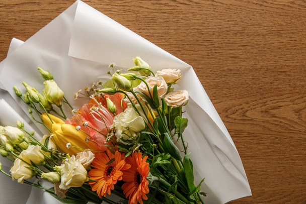 horní pohled na kvetoucí barevné jarní kytice na papíře na dřevěném pozadí - Fotografie, Obrázek