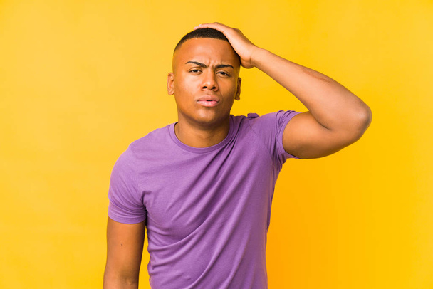 Young latin man isolated on yellow background tired and very sleepy keeping hand on head. - Foto, Bild
