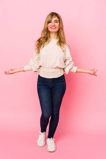 Jovem loira caucasiana mulher de pé sobre um fundo rosa mostrando uma expressão bem-vinda
. - Foto, Imagem