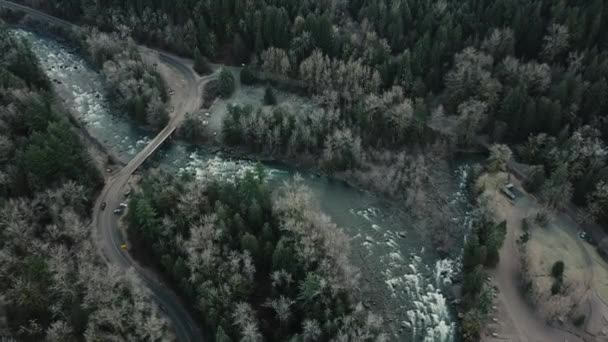 Leć nad drogą w kształcie litery S i małym samochodem przejeżdżającym przez most nad piękną niebieską rzeką - Materiał filmowy, wideo