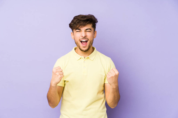 Young arabian man isolated on a purple background cheering carefree and excited. Victory concept. - Photo, Image