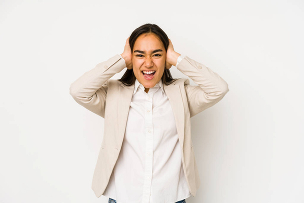 Young woman isolated on a white background covering ears with hands trying not to hear too loud sound. - Photo, image