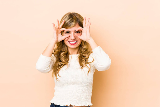 Young blonde caucasian woman excited keeping ok gesture on eye. - 写真・画像