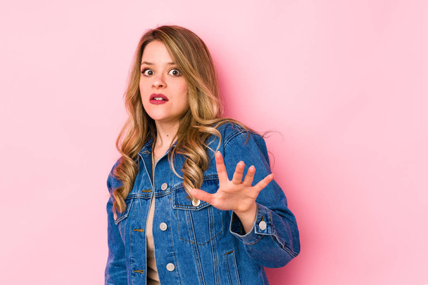 Young caucasian woman isolated on pink background being shocked due to an imminent danger - Photo, Image