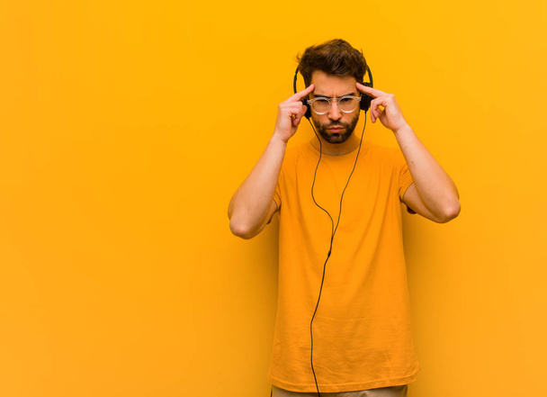 Mladý muž poslouchá hudbu a dělá soustředěné gesto - Fotografie, Obrázek