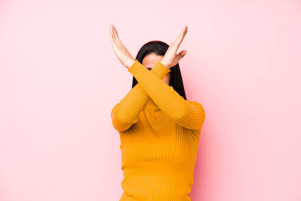 Young caucasian woman isolated on a pink background keeping two arms crossed, denial concept. - Foto, Imagen
