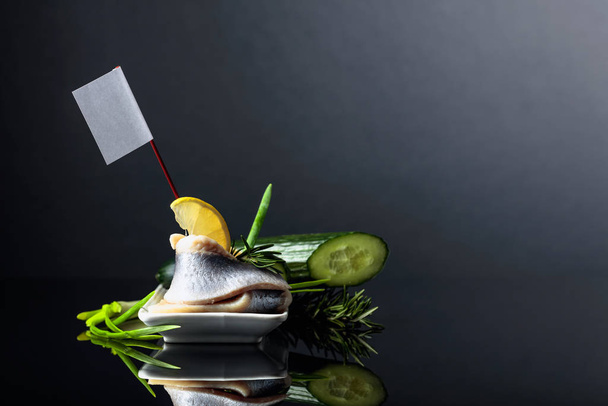 Atlantic herring with lemon, green cucumber, onion and rosemary. On white flag free space for your content. - Fotografie, Obrázek
