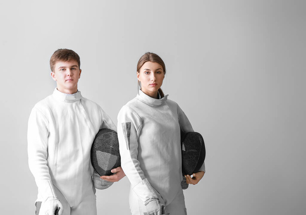 Young fencers on light background - Фото, изображение