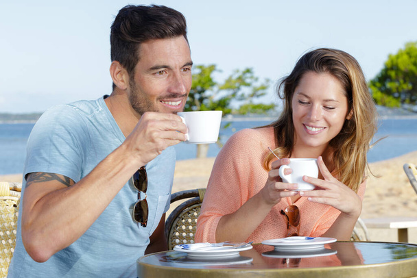 couple enjoying a drink on terrace of a beachside cafe - Φωτογραφία, εικόνα