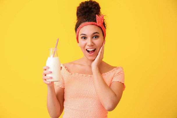 Young African-American woman with milk on color background - Foto, Imagem