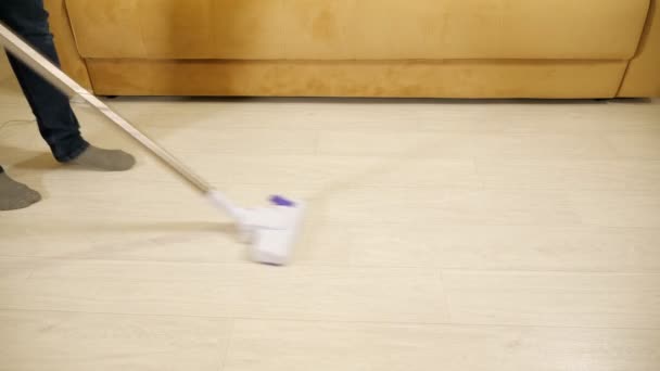 Úklid domu. Muž vysává podlahu s drátovým vysavačem - Záběry, video