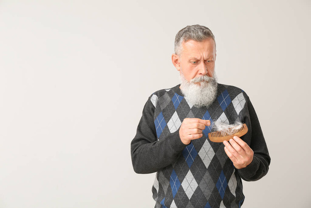Älterer Mann mit Haarausfall-Problem vor hellem Hintergrund - Foto, Bild
