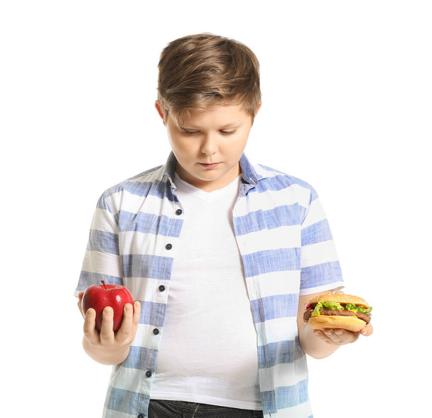 Ylipainoinen poika, jolla on omena ja hampurilainen valkoisella taustalla
 - Valokuva, kuva