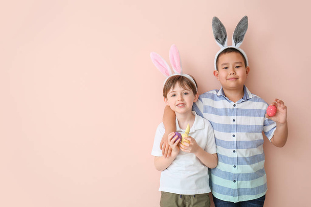 Маленькі хлопчики з великодніми яйцями та вухами кролика на кольоровому фоні
 - Фото, зображення