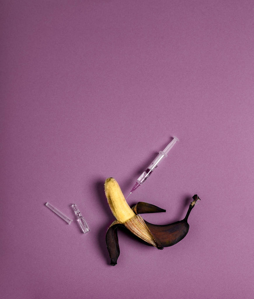 Medicine concept with rotten banana ampoule and injected syringe with liquid. Genetically modified fruit on cassis polyswatch background Copy space - Fotó, kép