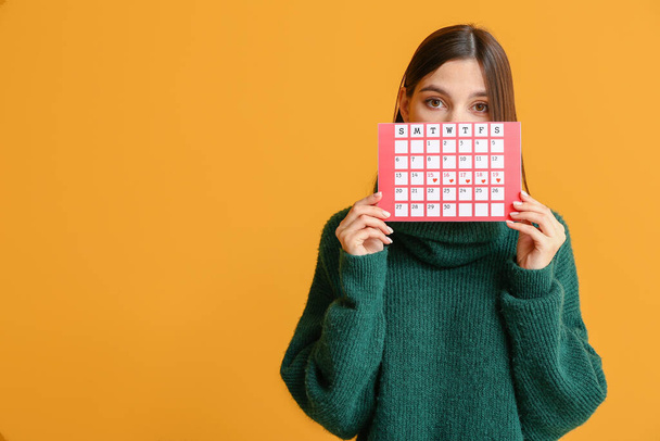 Young woman with menstrual calendar on color background - Photo, Image