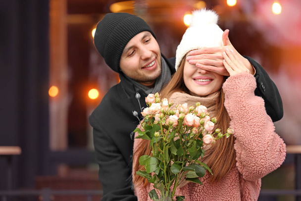 Beautiful young woman receiving flowers from her boyfriend on romantic date outdoors - Photo, Image