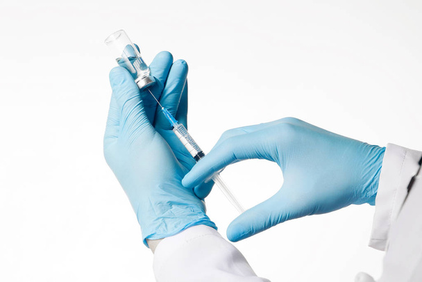 Feche o braço do médico usando seringa e ampola em fundo branco. Conceito médico, imunização e vacinação
 - Foto, Imagem