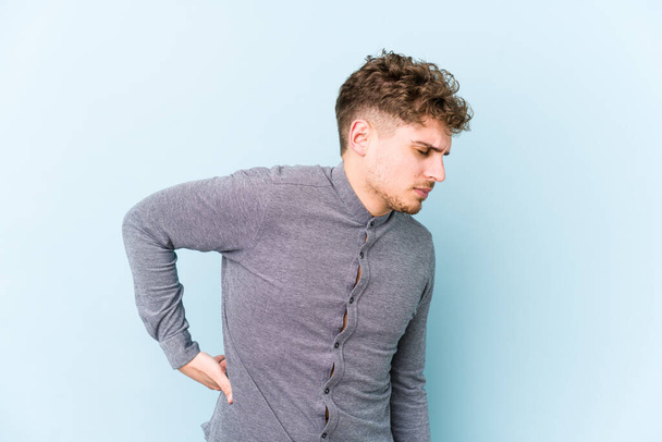Young blond curly hair caucasian man isolated suffering a back pain. - Photo, Image