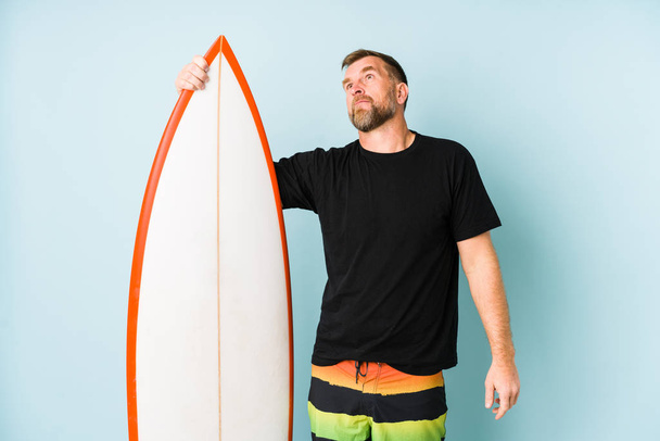 Surfen homme isolé sur fond bleu rêvant d'atteindre des objectifs et des buts
 - Photo, image