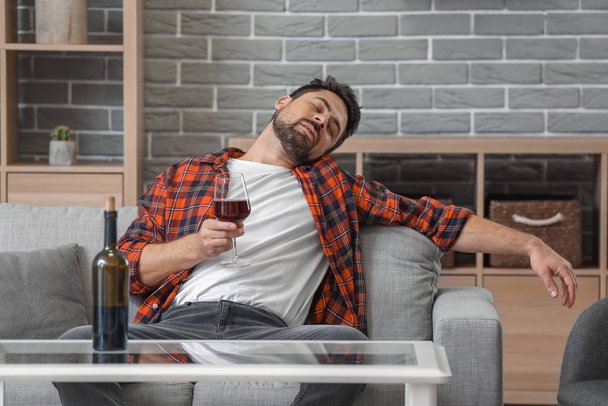 Чоловік п'є вино вдома. Концепція алкоголізму
 - Фото, зображення