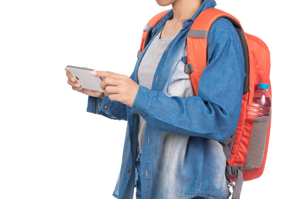 Femme en jeans avec sac à dos en utilisant smartphone mobile isolé sur fond blanc
. - Photo, image