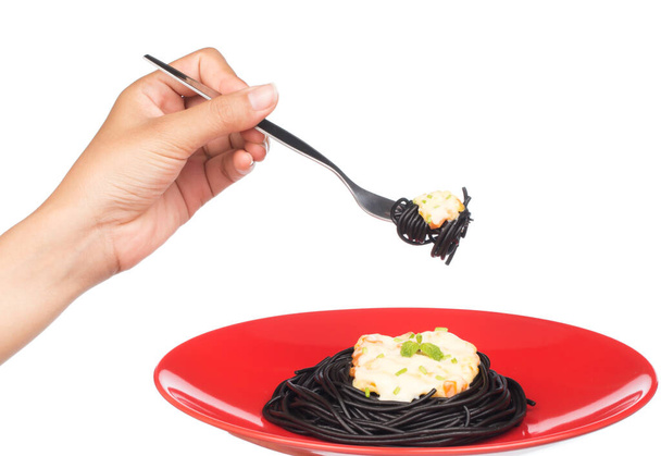 mão segurando rolo macarrão preto espaguete em um prato isolado no fundo branco
 - Foto, Imagem