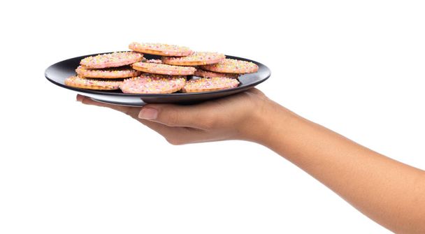 mano tenendo biscotti alla fragola con guarnizione cospargere su piatto isolato su sfondo bianco
. - Foto, immagini