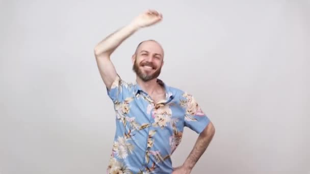 Heureux homme chauve barbu dansant et s'amusant sur fond blanc. Joyeux touriste portant chemise hawaïenne souriant
. - Séquence, vidéo
