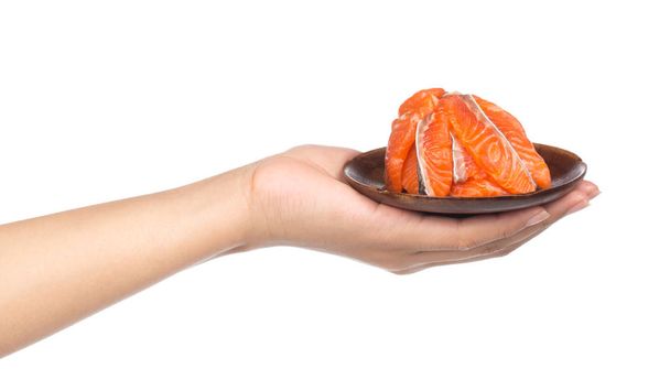 mão segurando fatia de peixe vermelho de salmão cru fresco em um prato de madeira isolado em um fundo branco
 - Foto, Imagem