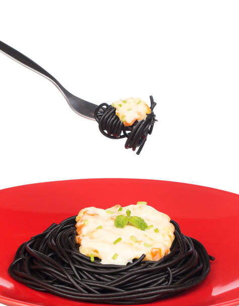 χέρι κρατώντας roll μαύρο ζυμαρικά σπαγγέτι σε ένα πιάτο που απομονώνονται σε λευκό φόντο - Φωτογραφία, εικόνα