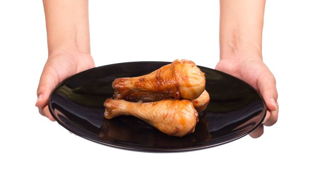 mão segurando perna de frango assado em um prato isolado no fundo branco
 - Foto, Imagem
