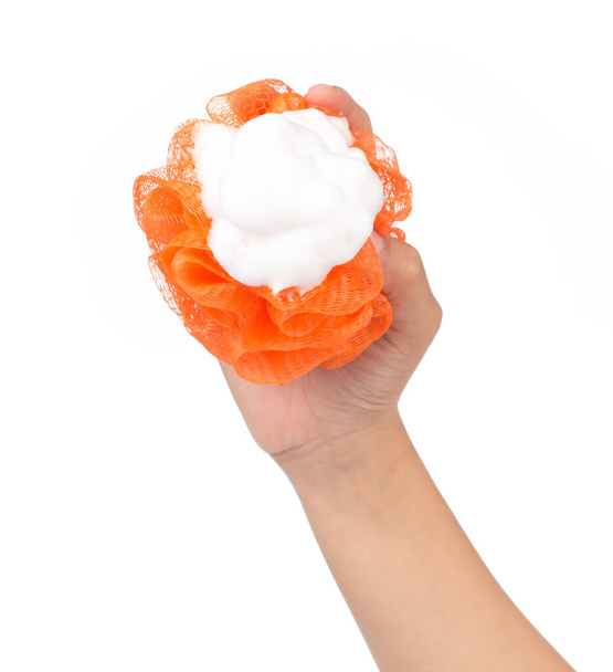 χέρι κρατώντας Μαλακό πορτοκαλί αφρόλουτρο ή σφουγγάρι απομονώνονται σε λευκό φόντο - Φωτογραφία, εικόνα