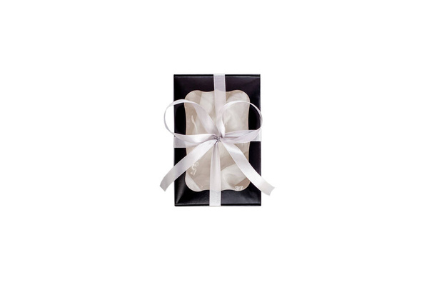 Zwarte geschenkdoos met zilveren lint geïsoleerd op witte achtergrond plat lay, bovenaanzicht. Monochrome kleuren trendy cadeau. Papier pakket met transparant venster voor mannen, vrouwen. Vakantie viering winkelen - Foto, afbeelding