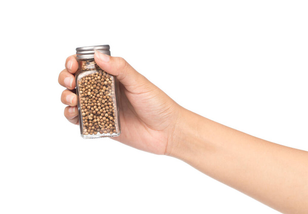рука тримає пляшку насіння коріандру ізольовано на білому тлі
 - Фото, зображення