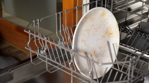 людина кладе брудний посуд і столові прибори в посудомийну машину крупним планом
 - Кадри, відео