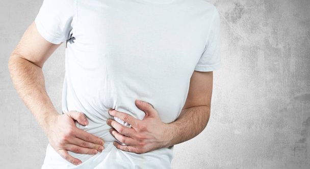 Abdominal pain. Medical and pharmaceutical concept. People's health problems, the man is holding his stomach, he feels pain. Stomach upset - Photo, Image