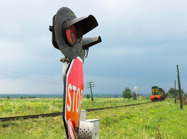 Semáforos y señales en el cruce del ferrocarril y el tren que se aproxima (Ucrania
). - Foto, Imagen