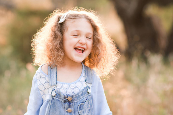 Smějící se holčička 3-4 roky se baví venku. Nosí stylové oblečení. Letní čas.  - Fotografie, Obrázek