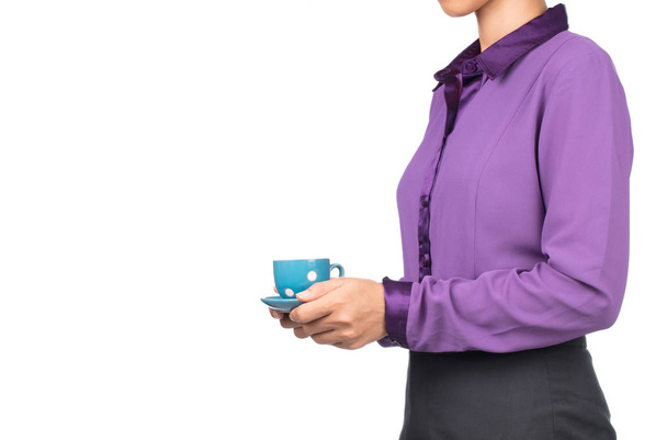 紫のシャツの美しい女性は白い背景に隔離されたコーヒーカップを保持しています - 写真・画像
