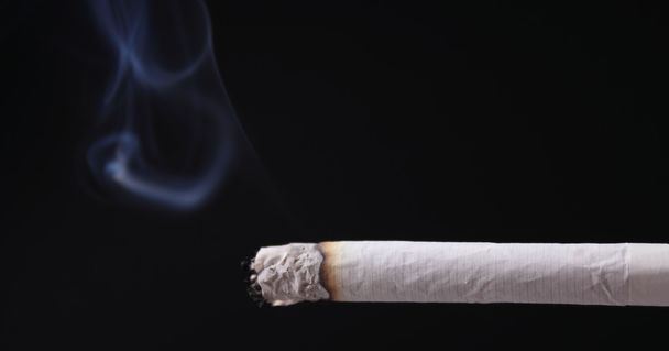 Cigarro sobre um fundo escuro
 - Foto, Imagem