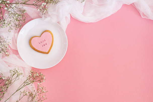 Ramitas de gypsophila y galletas con la inscripción Love you on a pink background. Fondo de primavera
 - Foto, Imagen