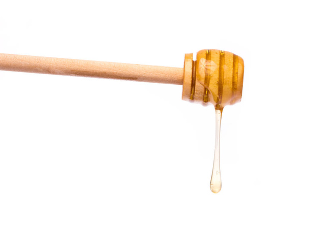 Mel pingando de um mergulhador de mel de madeira isolado no fundo branco
 - Foto, Imagem