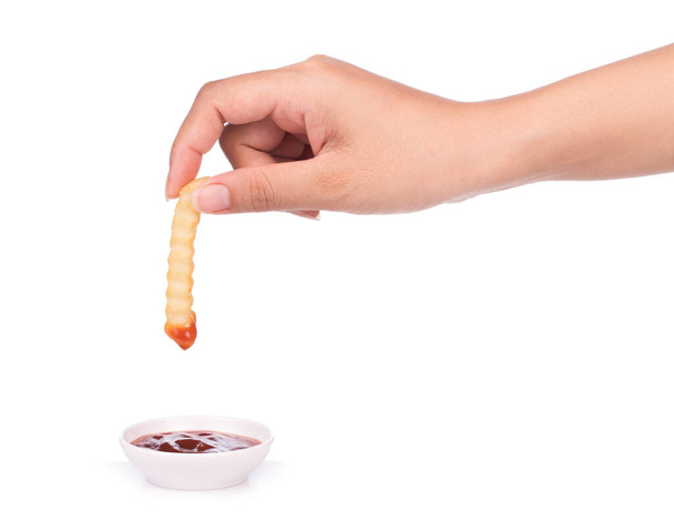 hand holding serrated french fries dip to tomato sauce isolated on a white background - Foto, Imagen