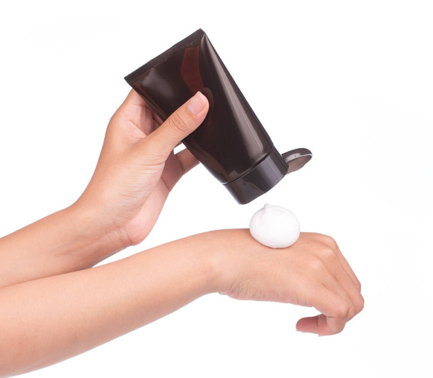 hands holding Cosmetic black plastic tube pouring foam on hand isolated on white background. - Foto, imagen