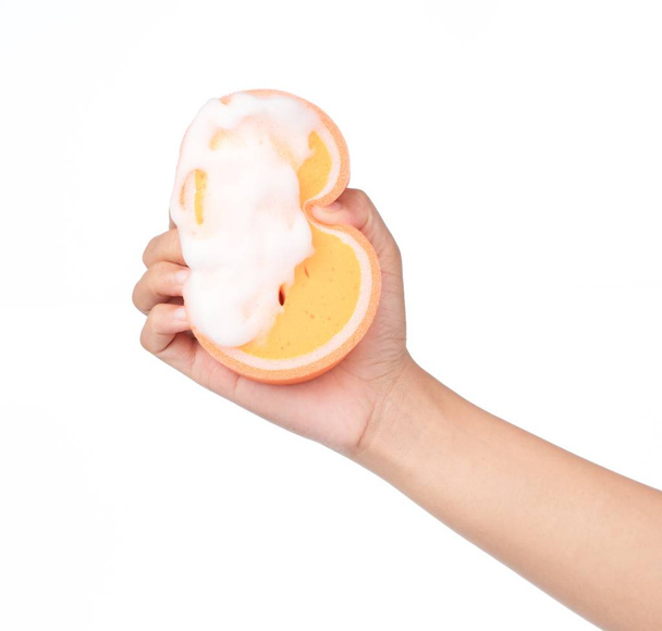 hand houden Oranje spons nat met schuim geïsoleerd op witte achtergrond. - Foto, afbeelding