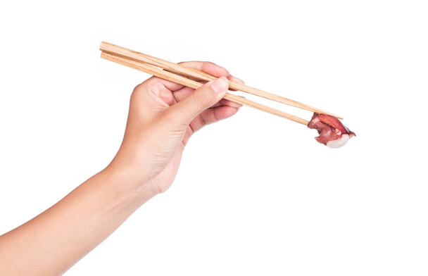 Рука тримає палички, їсть щупальця восьминога ізольовані на білому тлі
 - Фото, зображення